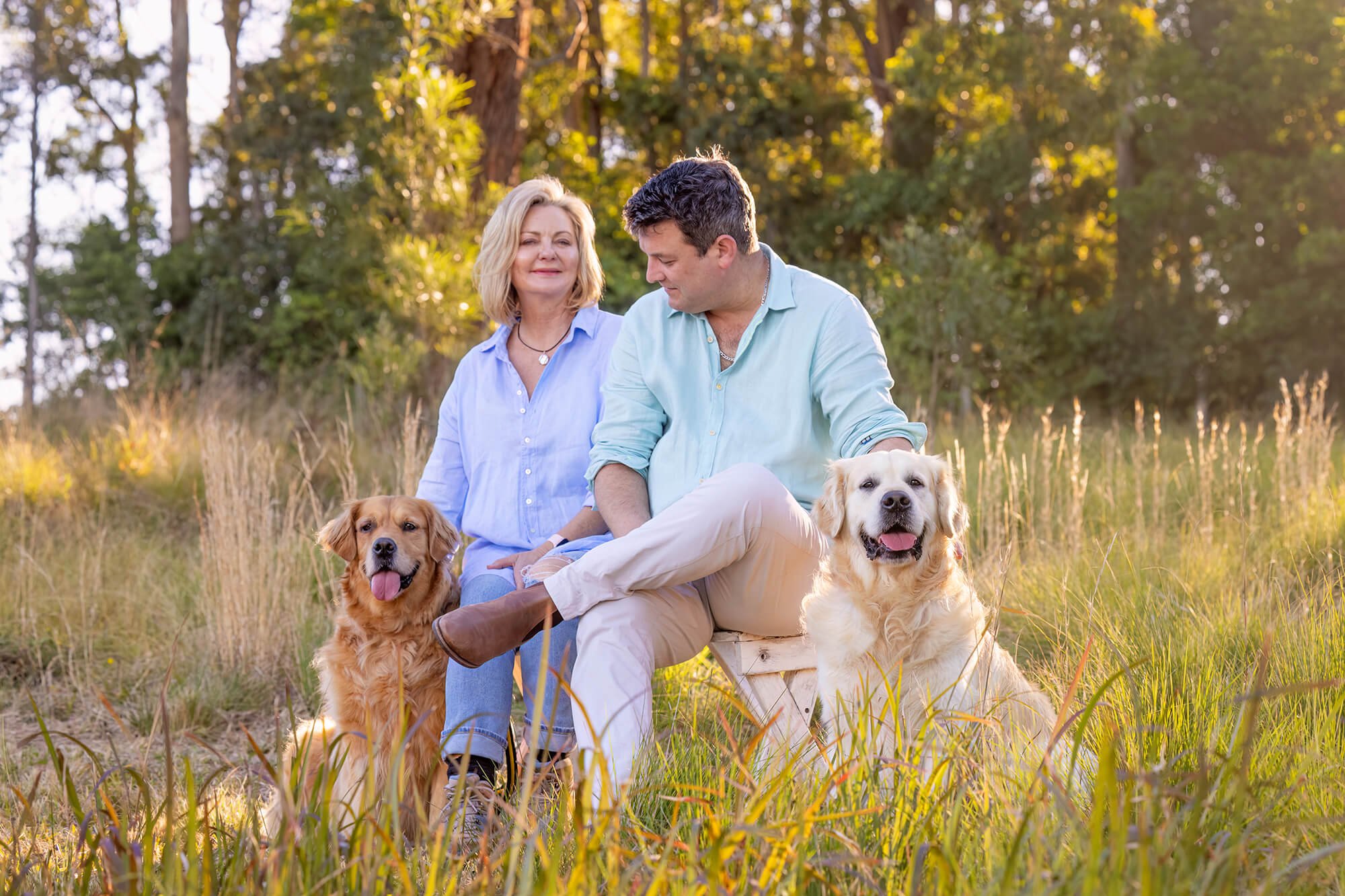 A couple relaxing with their Golden Retrievers during a countryside photo session at Jo Lyons Photography in Wootton